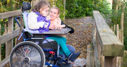 Child in a wheelchair enjoying outdoors with a carer