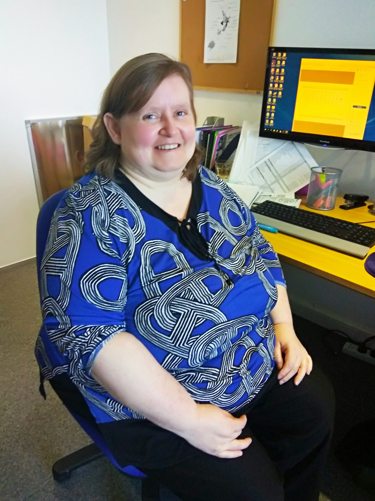 Kristina McKenzie sitting in front of a computer desk in an office.