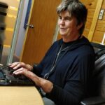Judy Small sits at an office desk using a braille machine