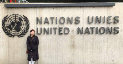 Teenager standing in front of wall with signage for the United Nations