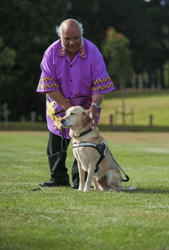 Image shows a man wearing a purple shirt with his service animal.