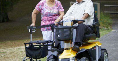 Older woman with rollator and oler man on mobility scooter at the park