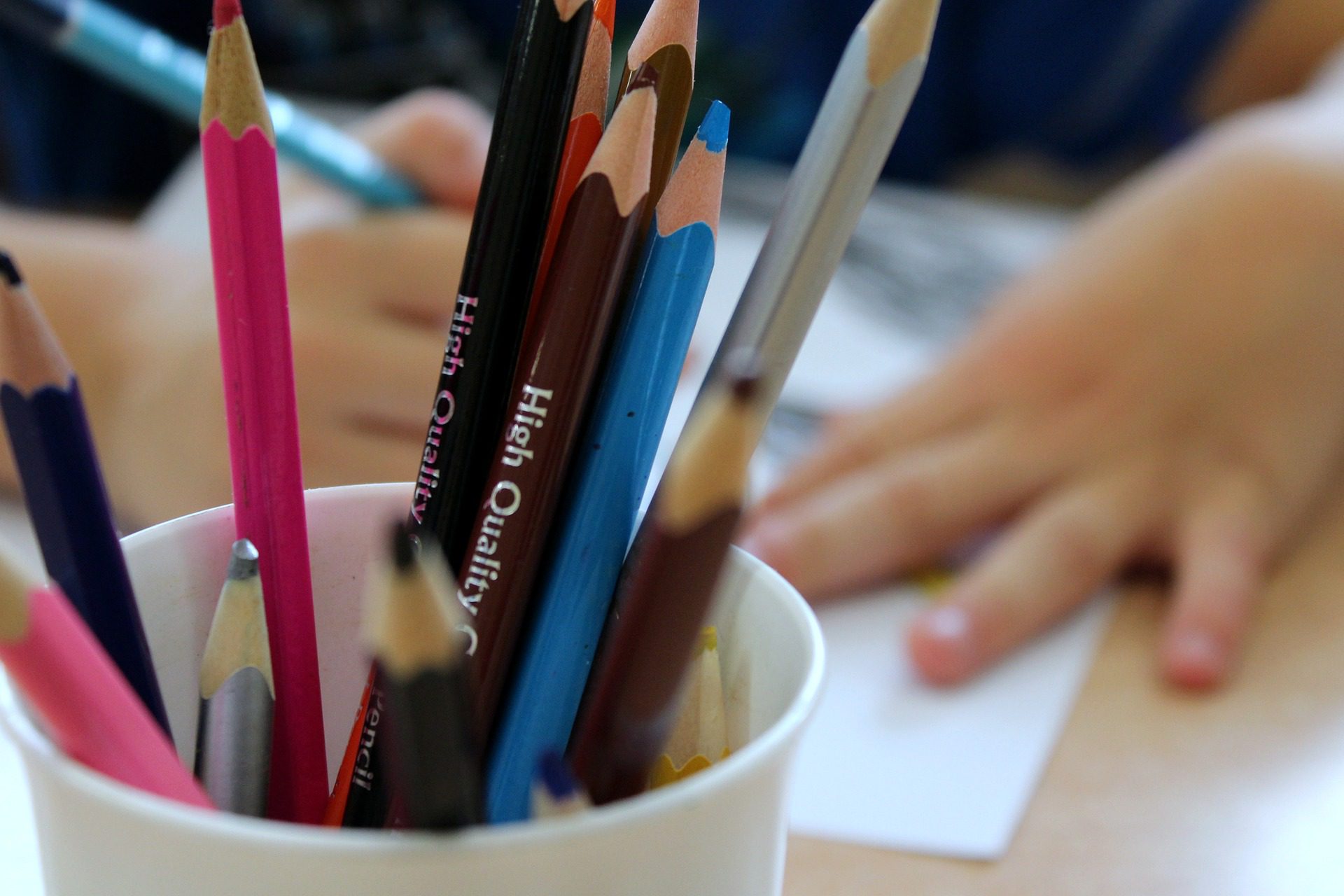 Jar of coloured pencils with child drawing in background