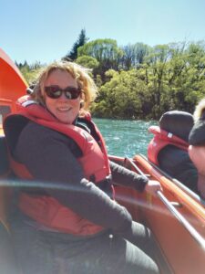 Suzie Linton has a broad smile and messy hair- on a jetboat in Queenstown in September 2020