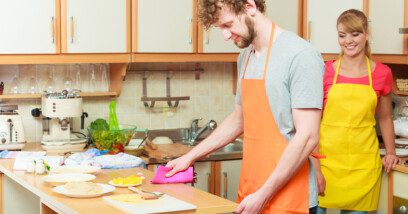 woman and man in apron cooking preparing dinner food in kitchen together.
