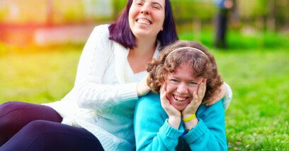 Two friends with learning disability sitting on lawn and laughing