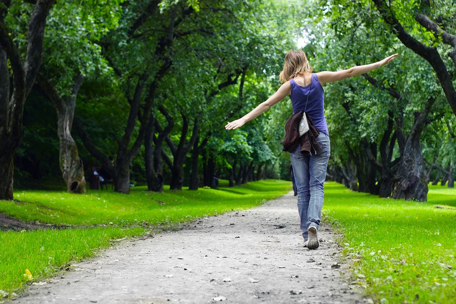 Woman walking on path in green summer park