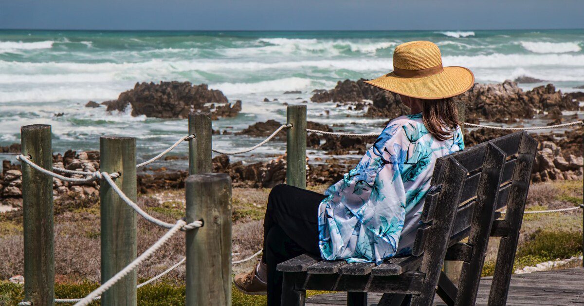 Woman sitting on a park bench by the sea